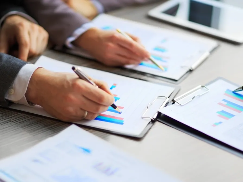 A group of people sitting at a table with papers.
